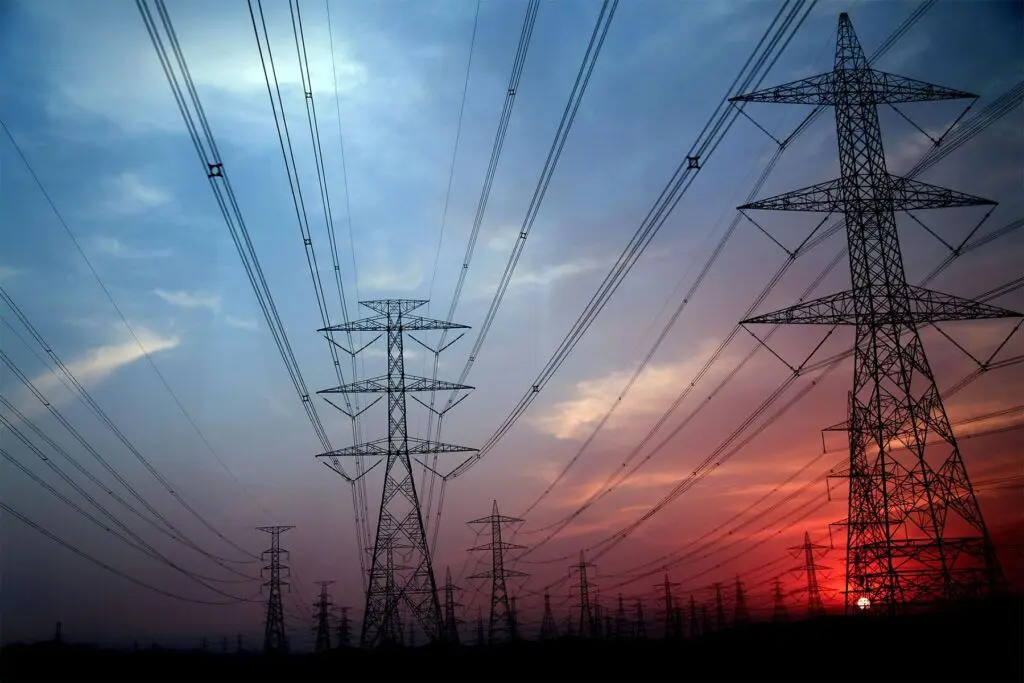 High-voltage power lines at sunset, symbolising the energy infrastructure and its environmental impact. - Kunak